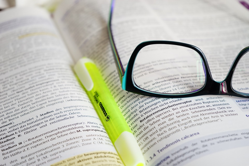 Offenes Buch mit Brille und Textmarker